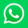 Top view of smartphone displaying WhatsApp logo on a wooden background, representing technology and communication.